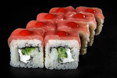 portre rulo suşi orkinos, salatalık ve philadelphia krem peynir kırmızı sos siyah arka plan üzerine hizmet süslenmiş