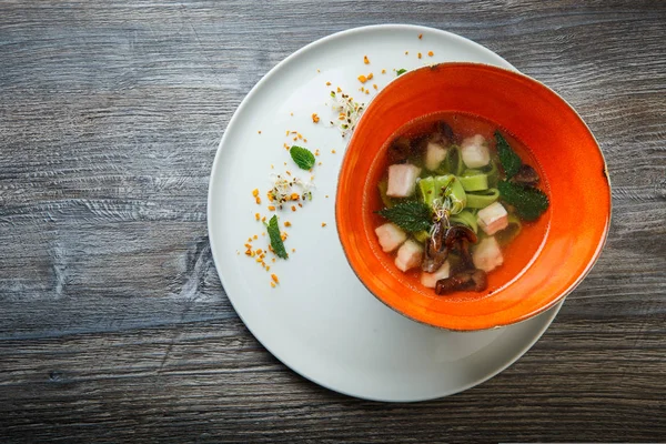 Top view delicious noodle soup with mushrooms, meat, and nettle leaves served in deep restaurant bowl on wooden table — Stock Image Top View Delicious Noodle Soup Mushrooms Meat Nettle Leaves Served Stock Photo