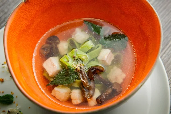 Closeup delicious noodle soup with mushrooms, meat, and nettle leaves served in deep restaurant bowl on wooden table — Stock Image Closeup Delicious Noodle Soup Mushrooms Meat Nettle Leaves Served Deep Stock Picture