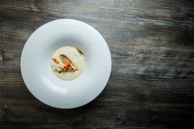 üstten görünüm beyaz balık krem çorbası kızarmış adet balık, karides ve derin beyaz Restoran plaka üzerinde ahşap masa servis baharatlar ile dekore edilmiş