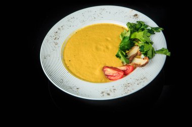 Vejetaryen krem çorba dilimlenmiş mantar, domates ve yeşil maydanoz ile dekore edilmiş restoran derin beyaz tabak siyah arka plan üzerine hizmet bırakır