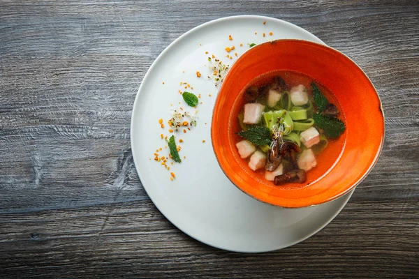 Top view delicious noodle soup with mushrooms, meat, and nettle leaves served in deep restaurant bowl on wooden table — Stock Image Top View Delicious Noodle Soup Mushrooms Meat Nettle Leaves Served Royalty Free Stock Photos