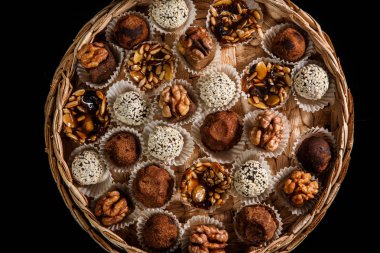 karamelize ayçiçeği ve kabak çekirdeği, kakao tozu, ceviz ve susam tohumu siyah arka plan üzerine dekore çeşitli sağlıklı yararlı el yapımı şekerlemeler ile dolu büyük bir el yapımı kutu üzerinde üstten görünüm