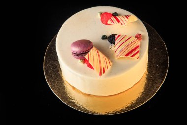 siyah arka plan üzerine beyaz sır mor macaron, çikolata renkli ve marmelat dekore edilmiş ile lezzetli yuvarlak pasta servis