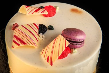 closeup ev yapımı yuvarlak kek çikolata renkli mor macaron ile dekore edilmiş beyaz sır ve siyah arka plan üzerine hizmet marmelat