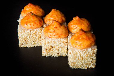 somon, yeşil soğan, philadelphia krem peynir ile Japon pişmiş rulo susam, peynir sos ve tobiko ile dekore edilmiş havyar, üstte siyah arka plan üzerine hizmet