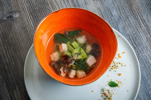 Delicious noodle soup with mushrooms, meat, and nettle leaves served in deep restaurant bowl on wooden table — Stock Image Delicious Noodle Soup Mushrooms Meat Nettle Leaves Served Deep Restaurant Stock Photo
