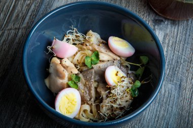 üstten görünüm portre erişte yemek shiitake mantar, tavuk yumurtası ve ahşap masa üzerinde derin siyah Restoran kasede servis buğday filizi ile