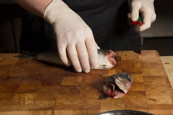 Chef-Hände in Handschuhen hacken Makrelenkopf ab — Stockfoto