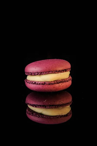 Single berry macaroon with yellow filling on black background — Stock Photo, Image