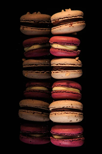 Row of colorful macaroons served on black background — Stock Photo, Image
