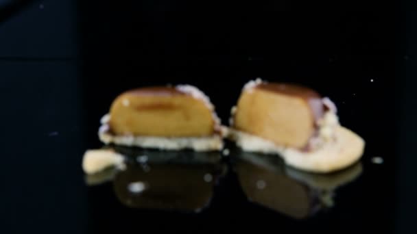 zoom avant sur tranché sur demi français mini dessert pâtissier mousse recouvert de glaçure chocolat et décoré de noix concassées sur fond miroir noir 