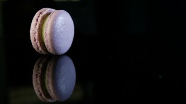 closeup panorama Menekşe üzerinde Fransız tatlı macaron birlikte yeşil krem dolum kenarında siyah yansıma ile