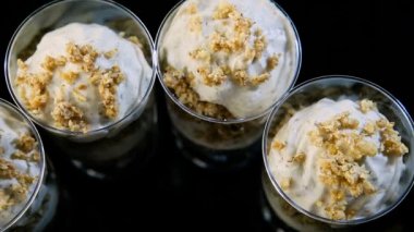 siyah arka plan üzerine küçük yuvarlak plastik bardaklarda servis granola insan eli beş beyaz banana Mus tatlı koymak süslenmiş