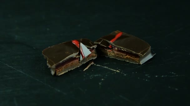 キャラメル充填で半分の小さな正方形チョコレート菓子のカットの上から見る黒の台所のテーブルで提供しています — ストック動画