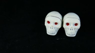 insan eli üç beyaz çikolata şekerleme iskelet kafatası şekli kırmızı gözlü siyah arka plan üzerine koymak