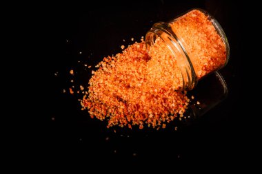 Üstten Görünüm büyük portakal organik deniz tuzu küçük cam kavanozdan dışarı dökülür