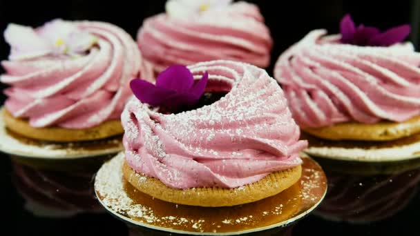 从用紫罗兰色和白色花朵装饰的一小群粉红色棉花糖饼干中缩小 — 图库视频影像