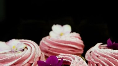 küçük grup mor ve beyaz çiçeklerle süslenmiş pembe hatmi çerezleri üzerinde aşağı makro panorama