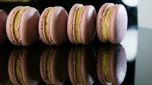 Human hand takes away one by one violet macaroon from one row — Stock Video