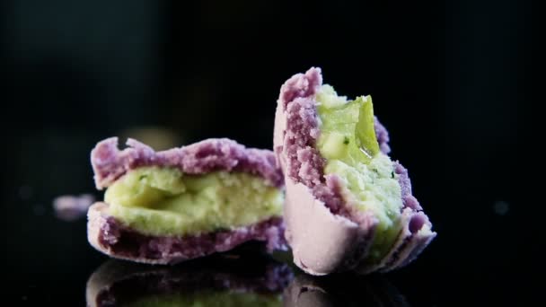 Close-up quebrado na metade violeta francês macaroon no fundo preto — Vídeo de Stock
