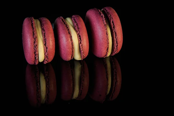 Three purple macaroons with yellow filling lie on edge — Stock Photo, Image