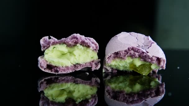 Крупным планом две половинки сломанного фиолетового французского макарона с отражением — стоковое видео