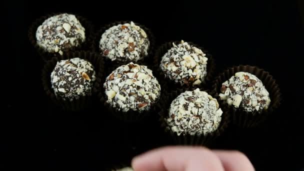 特写制作糖果手把许多圆球巧克力糖果装饰与粉碎坚果在黑色背景 — 图库视频影像