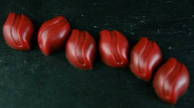 Kırmızı oval şekilli çikolata şekerleme siyah tablo arka plan üzerinde hizmet closeup satır içinde odak