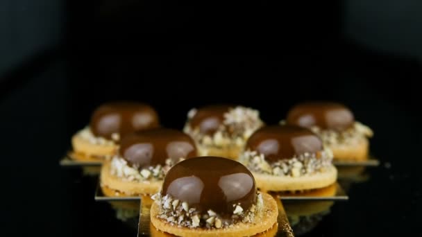 フランス語のダウンのセット上のパノラマ ムース デザート菓子チョコレート釉の黒い背景に三角形の形で提供しています — ストック動画