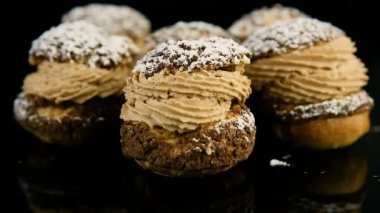 Fransız tatlılar choux pasta siyah ayna arka plan yansıması üzerine alınarak krem karamel ile dolu, closeup panorama üzerinden aşağı ayarla