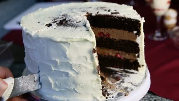 クローズ アップ人間の手スライス大きな結婚式チョコレート ケーキとキャラメル充填チェリー ホワイト クリームで飾られました — ストック動画