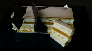 siyah arka plan üzerine hizmet çikolata dolum jöle ile çok katmanlı karamelli pasta dilimlenmiş parça odak süslenmiş