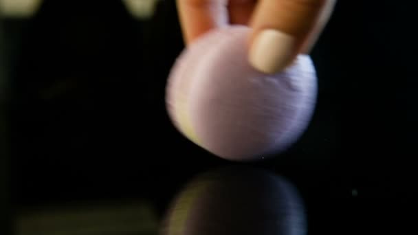 main humaine faire tourner violet dessert français macaron avec remplissage crémeux vert sur fond miroir noir avec réflexion 