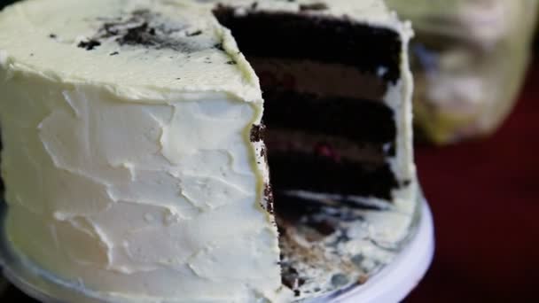人类的手旋转大巧克力蛋糕与焦糖和樱桃填充装饰白色奶油 — 图库视频影像