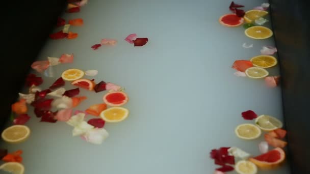 Närbild varmt bad med mjölk, citrus skivor, och rosenblad — Stockvideo