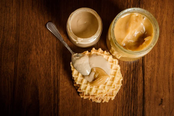 Top view on jars with honey and tahini, and belgian waffles — Stock Photo, Image