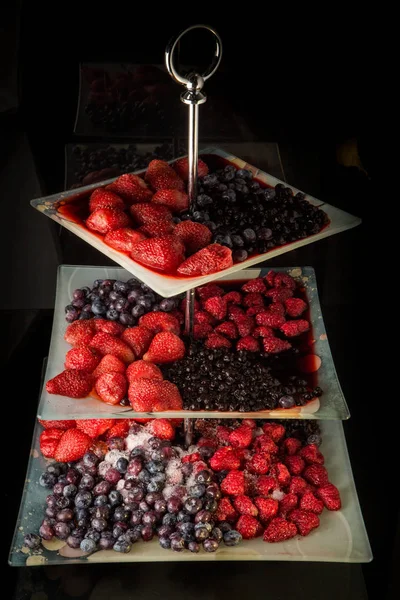 Различные замороженные оттаявшие ягоды подаются на трех нишах тарелки — стоковое фото