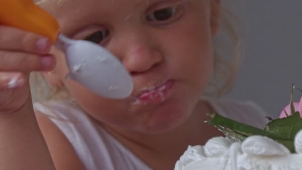 特写金发小女孩吃一小块用玫瑰装饰的白色乳白色婚礼蛋糕 — 图库视频影像