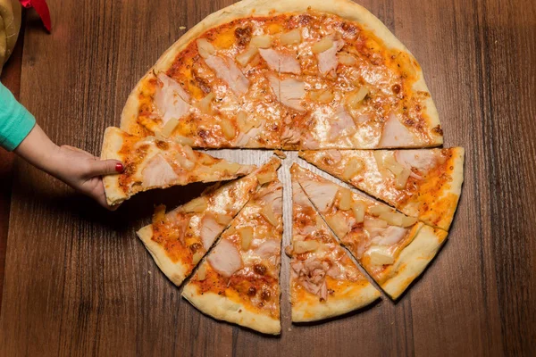 Рука ребенка взять один кусок пиццы с кусочками прошутто — стоковое фото
