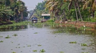 Hindistan 'da asma köprü altında palmiye kıyıları boyunca sakin nehir boyunca uzanan büyük turistik tekne.