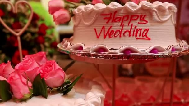 バラと赤キャラメルの銘文で飾られたおいしい白いクリーム色のウェディングケーキ — ストック動画