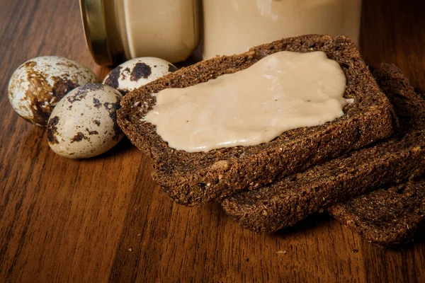 Closeup three rye bread slices with tahini butter next to quail eggs — Stock Photo, Image