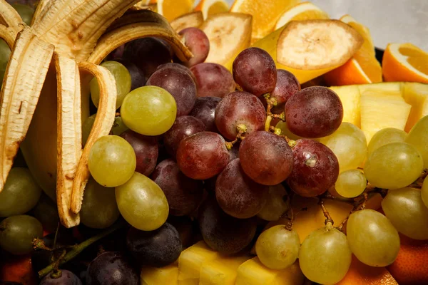 Vista superior close-up uvas variadas e frutas tropicais fatiadas — Fotografia de Stock
