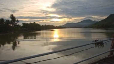 Nha Trang, Khanh Hoa / Vietnam - Temmuz 2016: Nha trang 'da 3 Temmuz' da nehre yansıyan bulutlu gün batımına karşı ahşap köprüden ahşap nehir manzaralı geniş sakin nehir manzarası