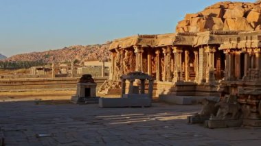 Büyük gölgeli tarihi bina manzarası ve Hampi 'de birçok sütunu olan antik kayalık bina.