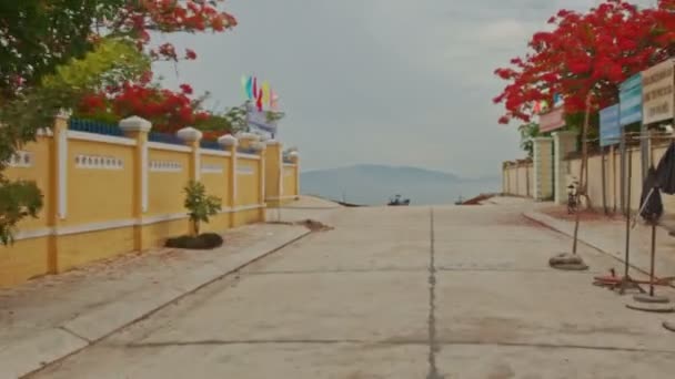 Nha Trang Khanh Hoa Vietnam 2016年6月26日 6月26日 在越南Nha Trang 摄相机沿着村庄街道在黄色村庄之间的花卉树与海上船只直接靠岸 — 图库视频影像