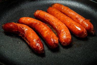 yuvarlak siyah tavada closeup beş kısa kızarmış avcılık sosis