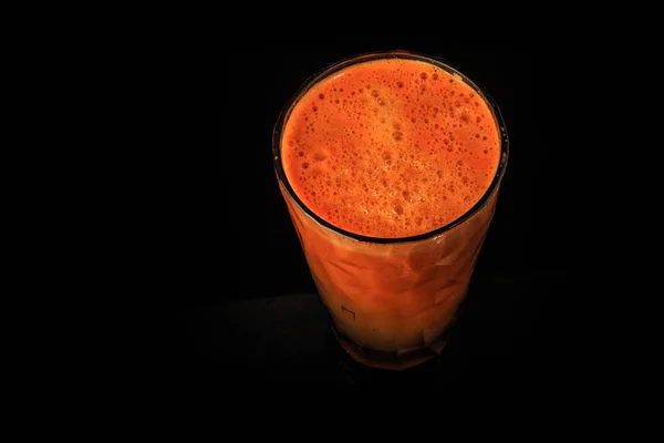 Top view on tall faceted glass of raw fresh carrot juice — Stock Photo, Image
