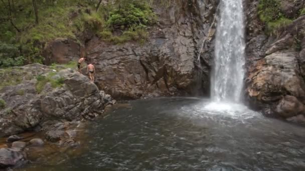 Mann Schwimmt Tropischen Nationalpark Wasserfall Schaumspritzern Zwischen Felsigen Ufern — Stockvideo